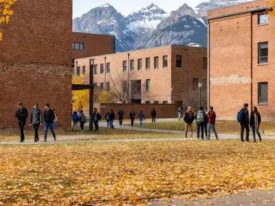 A university campus quad with brick buildings and students walking in autumn.