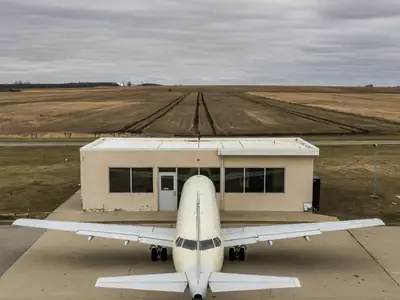 A small regional airport terminal with a single jet parked at the gate.