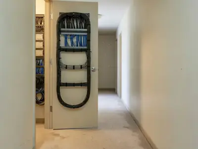 A condo building hallway with a telecom closet door open showing neat bundled cables.