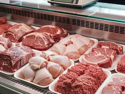 A butcher counter display case with roasts, chicken thighs, pork chops and ground beef on trays.