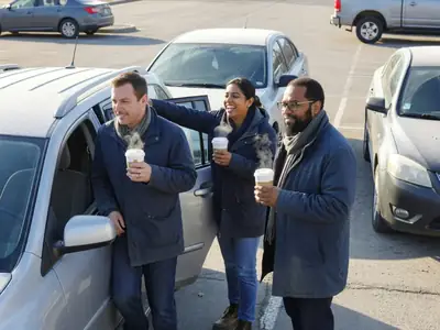Three co-workers getting into a small SUV together in an office parking lot in the morning.