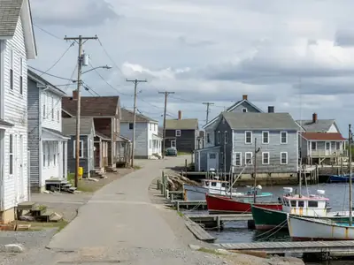 A small fishing village with wooden houses and utility poles along a coastal road.