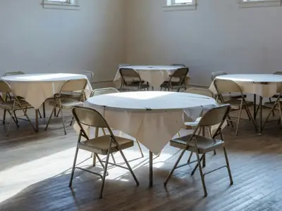 An empty community hall set up for a party with round tables and folding chairs.
