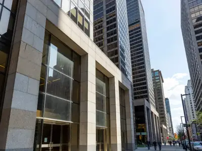 The stone and glass entrances of big bank towers on a downtown financial-district street.