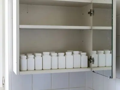 A medicine cabinet with plain white bottles of pain relievers and allergy tablets lined up.