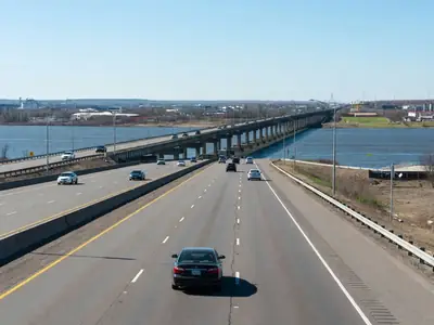 A car on a highway approaching a long bridge over a river at a border city.